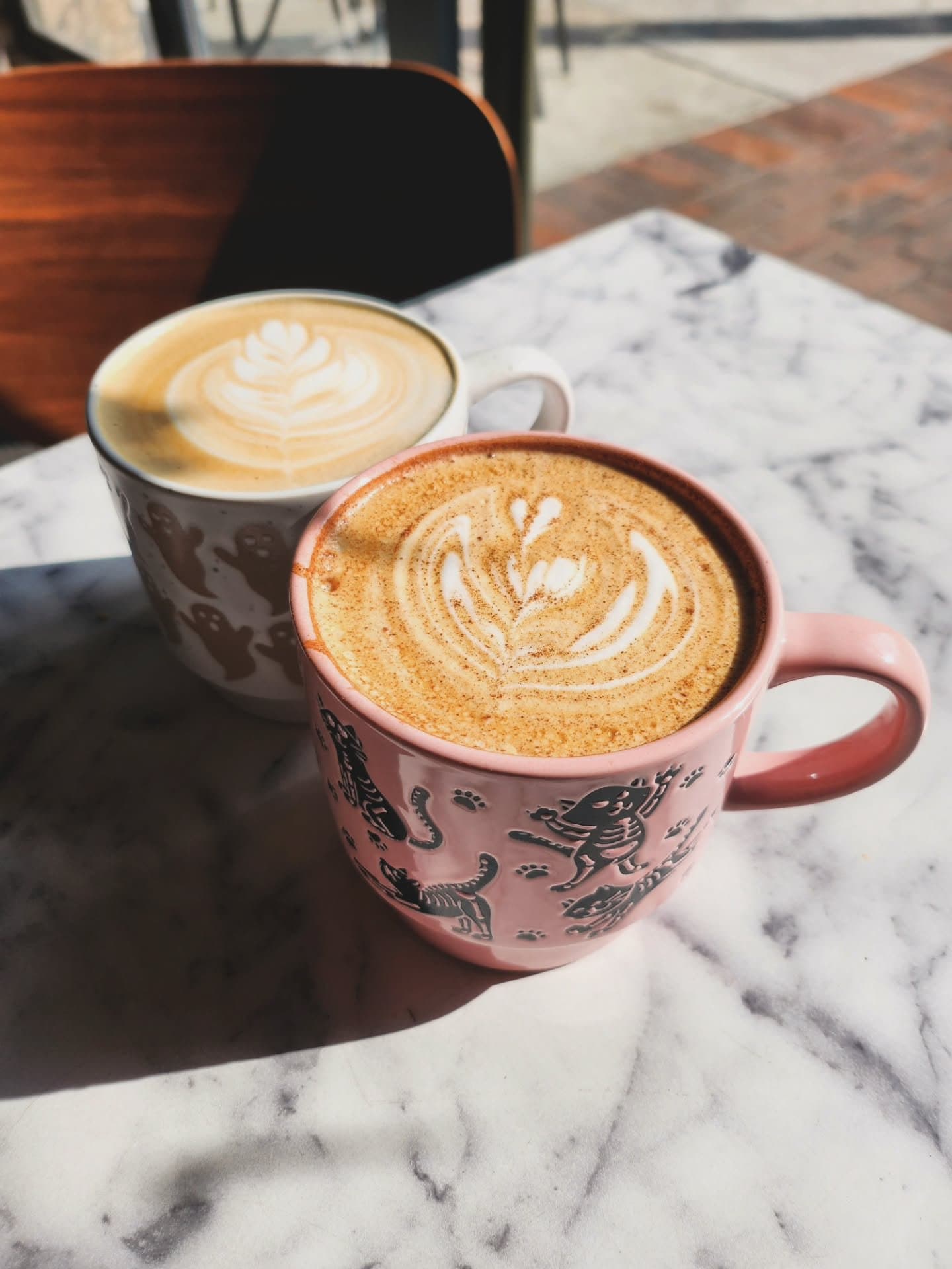 Latte with leaf art beside stacked assorted donuts on dark table against exposed brick wall 5