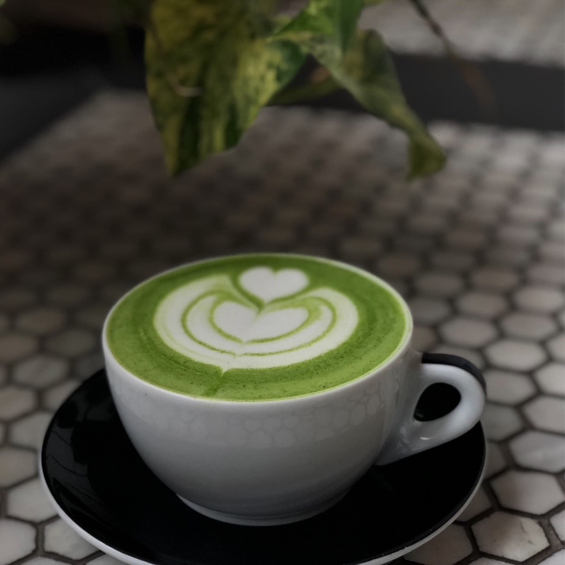Latte with leaf art beside stacked assorted donuts on dark table against exposed brick wall 7