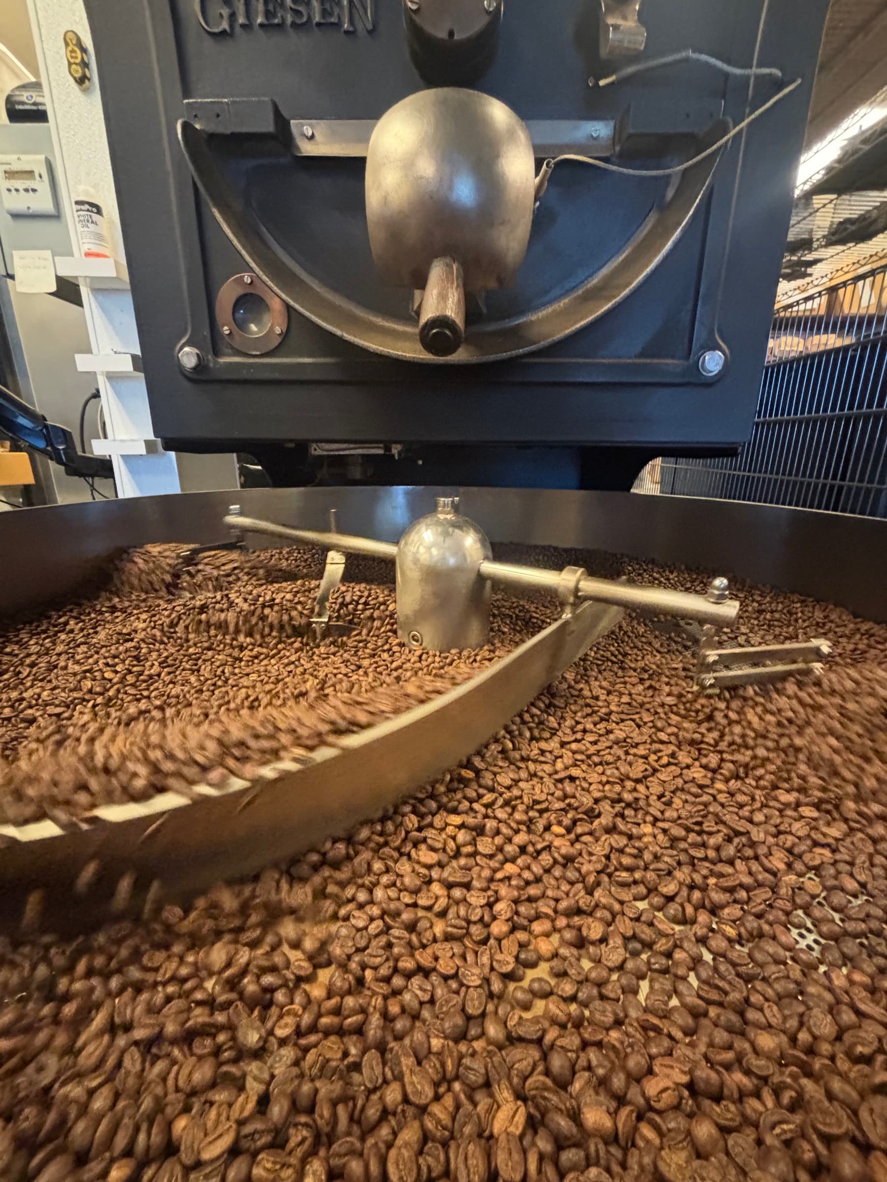 Latte with leaf art beside stacked assorted donuts on dark table against exposed brick wall 3